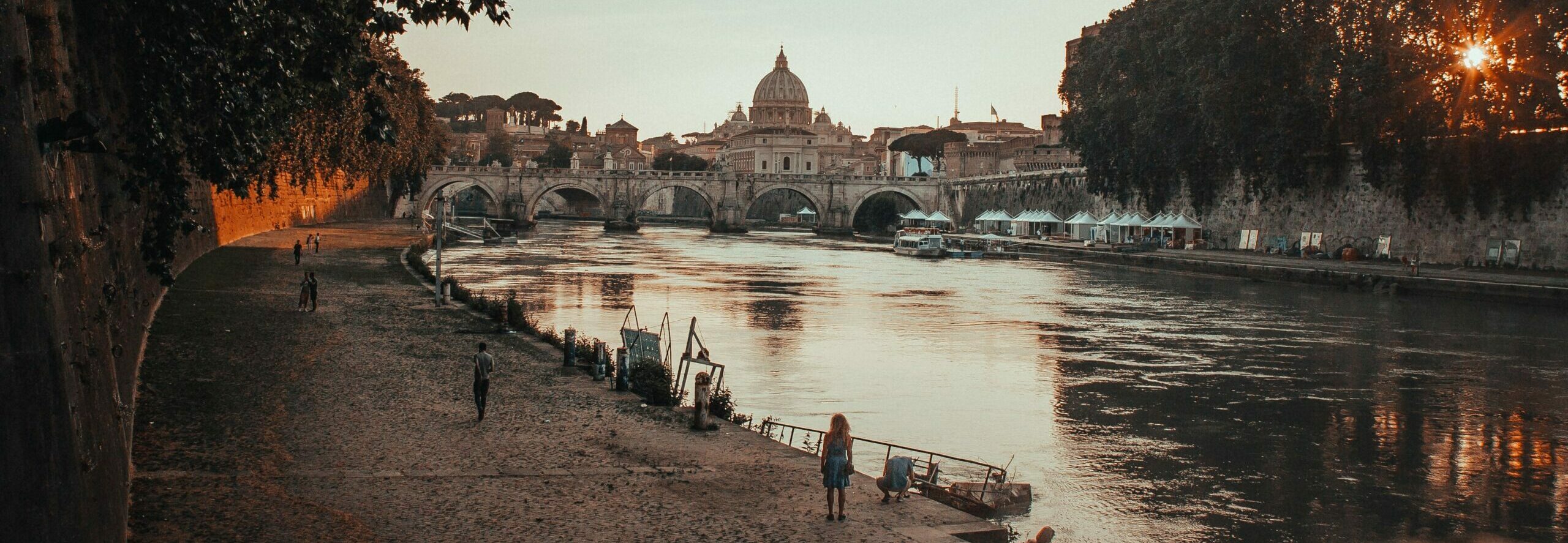 Beautiful shot of a black concrete pathway beside the body of waterin Rome, Italy during sunset
